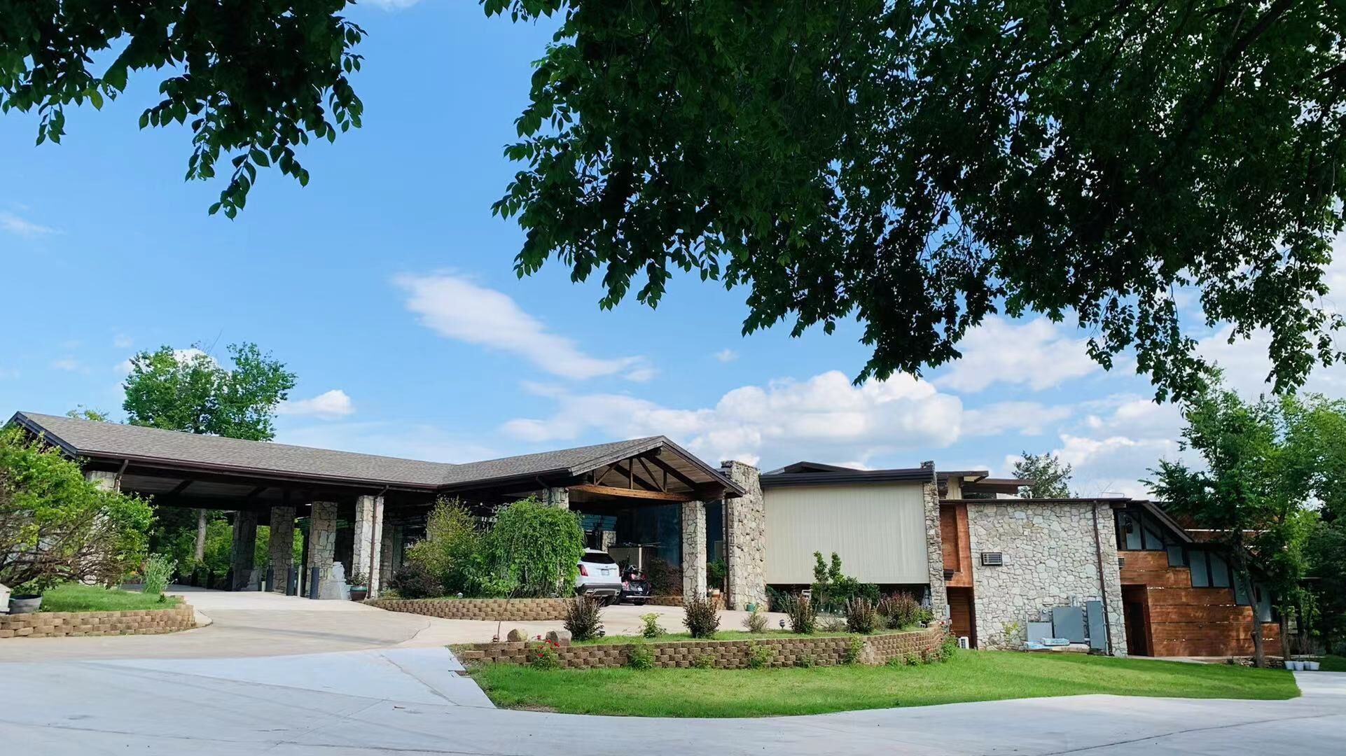 A modern two-story house with a stone facade, a covered porch, and a well-maintained lawn.