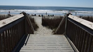 Una passerella di legno che conduce a una spiaggia sabbiosa con vista sull'oceano.