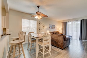 A spacious living area with a dining table, chairs, a sofa, and a ceiling fan.