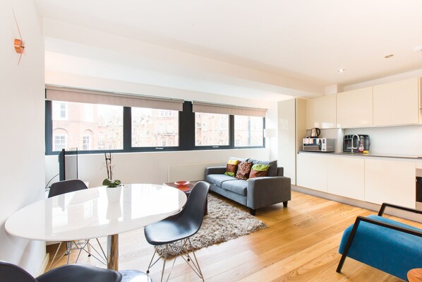 Eine moderne Wohnung mit Essbereich, Sofa und Küche.