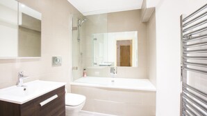 A modern bathroom with a vanity, toilet, bathtub, and a glass shower enclosure. - Spacious 1 Bedroom Apartment in Kensington - A2 (London)