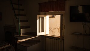 A room with a staircase, a radiator, a television, and a window with a curtain.