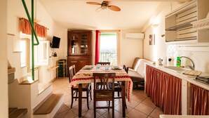 A dining area with a table set for four, a kitchen with a sink and cabinets, and a ceiling fan.