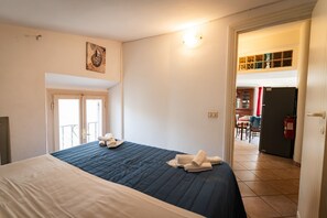 Ein Hotelzimmer mit Bett, einer Tür zu einem Balkon und Blick auf den Speisesaal.