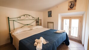 A bedroom with a bed, a radiator, and a door leading to a balcony.