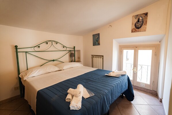 A bedroom with a bed, a radiator, and a door leading to a balcony.