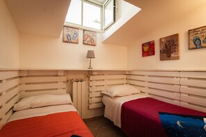 Ein Schlafzimmer mit zwei Betten, einem Dachfenster und drei Wandbildern.
