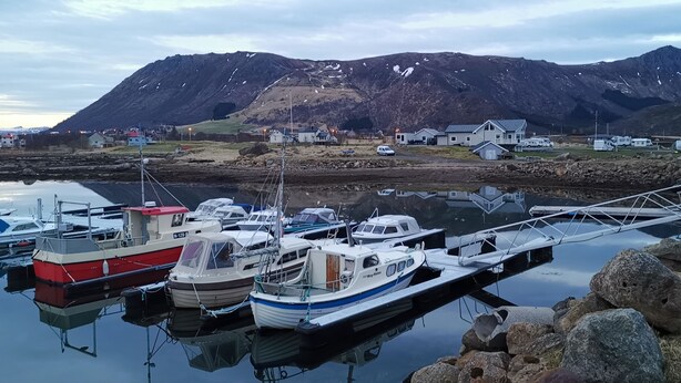 A marina with boats docked, a bridge, and houses in the background. - Oppmyre Camping (Oksnes)