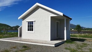 A small, single-story house with a gabled roof, a front porch, and a window. - Oppmyre Camping (Oksnes)