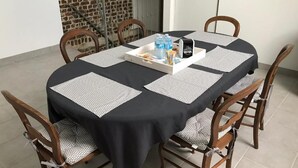 Een ronde eettafel met een zwarte tafelkleed en witte placematen, omringd door houten stoelen met gestreept kussen.