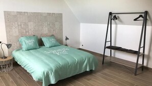 Een slaapkamer met een bed, een hangstoel en een wandplank.