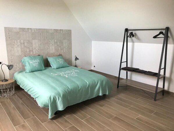 A bedroom with a bed, a hanging chair, and a wall-mounted shelf.