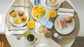 Ein Esstisch mit verschiedenen Speisen, darunter Eier, Toast, Obst und Kaffee.