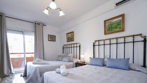 Une chambre d’hôtel avec deux lits, un balcon et un tableau au mur.