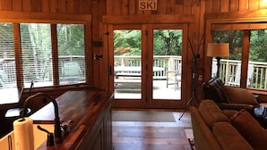 Interior d'una cabana de fusta amb zona de cuina, taula de dinar i sofà.