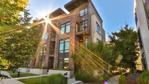 A modern building with a brick facade, large windows, and a courtyard with benches and greenery. - Downtown Walla Walla Townhome · Walk to Main St · Rooftop + Garage (Walla Walla)