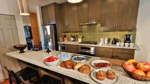 A kitchen with wooden cabinets, a granite countertop, and various breakfast items. - Downtown Walla Walla Townhome · Walk to Main St · Rooftop + Garage (Walla Walla)
