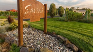 A sign with the name 'Saviath Cellars' in a landscaped area with a well-maintained lawn, rocks, and shrubs. - Downtown Walla Walla Townhome · Walk to Main St · Rooftop + Garage (Walla Walla)