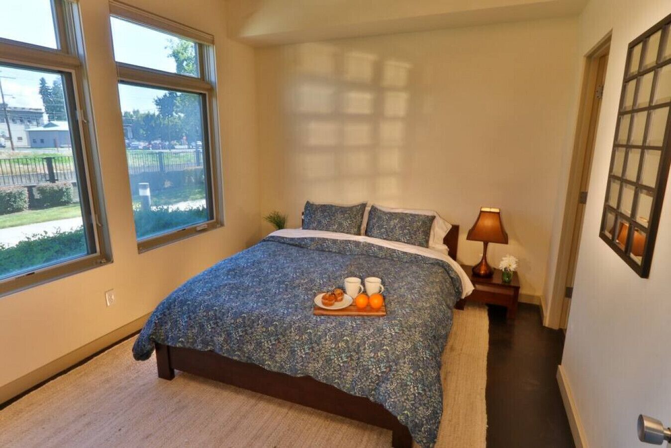 Un dormitorio con una cama grande, una mesita de noche con lámpara y una ventana que ofrece vistas al exterior.