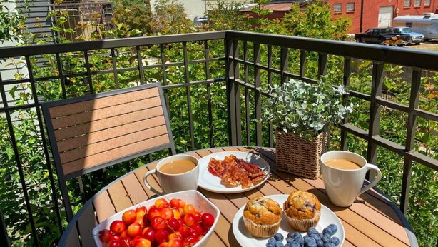 A balcony with a table set for breakfast, including cherries, muffins, and coffee. - Downtown Walla Walla Townhome · Walk to Main St · Rooftop + Garage (Walla Walla)