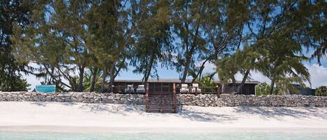 A beachfront property with a stone wall, a wooden deck, and a building with a roof.