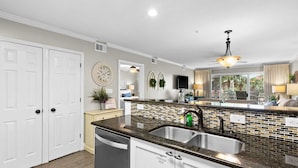 Una cocina con encimera de granito, pileta de acero inoxidable y muebles blancos.