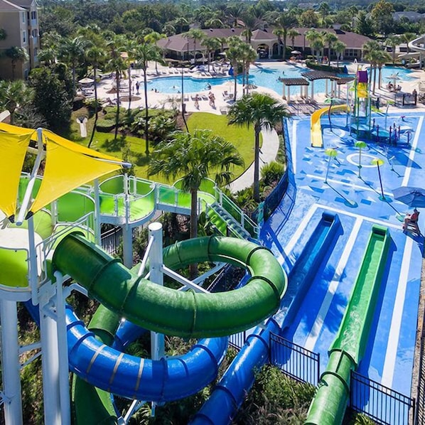 A water park with multiple slides and pools, surrounded by palm trees and hotel buildings.