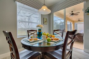 Enjoy meals with friends and family in this cozy dining area, featuring a round table for four, a vase with fresh flowers, and a selection of pastries.