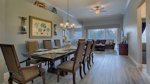 A spacious dining area with a large wooden table and matching chairs, a chandelier, and a ceiling fan. - Welcome to The Windsor Fantasy with Brand New Professional Arcade Room! (Kissimmee)