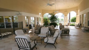 A spacious indoor patio with multiple seating areas, large windows, and ceiling fans. - Welcome to The Windsor Fantasy with Brand New Professional Arcade Room! (Kissimmee)