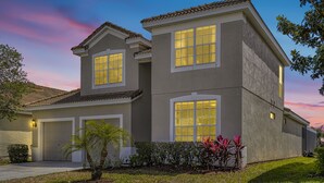 A two-story house with a garage, large windows, and a well-maintained lawn.