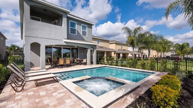 A modern two-story house with a swimming pool, outdoor seating, and a fenced garden area. - Delightful Home with Entertainment Loft at Encore (Kissimmee)