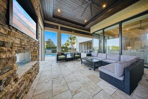 Un espacio de patio al aire libre con paredes de piedra, cerramiento de vidrio y mobiliario exterior.
