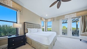 Un dormitorio con una cama grande, una mesita de noche, una lámpara y vistas al exterior a través de una puerta corredera.