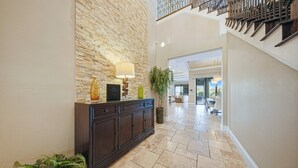 Un vestíbulo con pared de piedra, una consola de madera oscura, una lámpara y una planta en maceta.