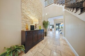 A lobby with a stone wall, a dark wooden console, a lamp, and a potted plant.