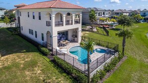 Ein zweigeschossiges Haus mit Swimmingpool, Balkon und gepflegtem Rasen.
