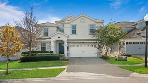 A two-story house with a garage, a driveway, and a well-maintained lawn. - Bright Villa with Theater in Champions Gate (Davenport)
