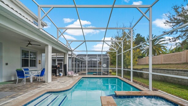 A swimming pool with a hot tub, covered patio area, and outdoor seating. - Bright Villa with Theater in Champions Gate (Davenport)