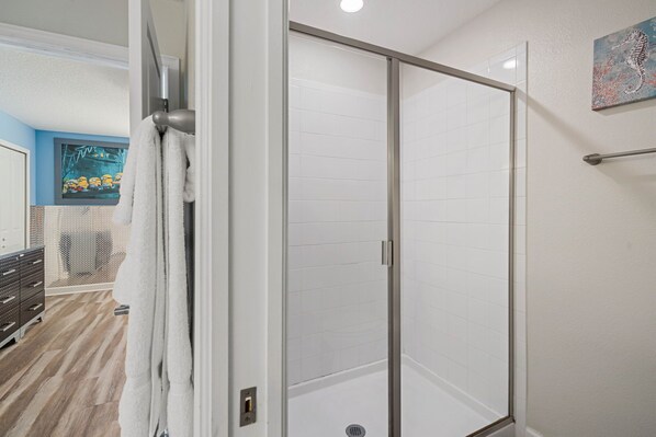A modern bathroom with a glass shower enclosure, a towel rack, and a painting on the wall. - 8BR ChampionsGate Villa | Theater, Pool & Games (Davenport)