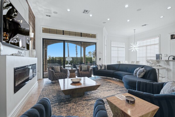 A spacious living room with a fireplace, comfortable seating, and large windows offering a view.