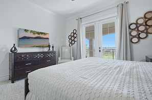 Une chambre à coucher avec un lit, une commode et un tableau représentant un paysage.