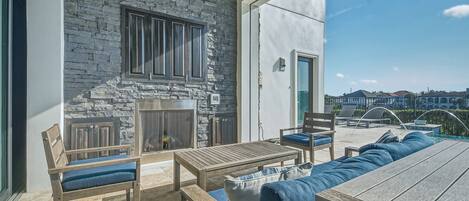 A patio with stone walls, a fireplace, outdoor seating, and a view of neighboring houses.