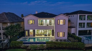 A two-story house with a swimming pool, a balcony, and a well-maintained garden. - Sun-Filled Haven with Sports Themed Game Room at Reunion (Reunion)