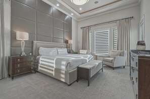 A modern bedroom with a large bed, bedside tables, a chair, and a dresser. - Sun-Filled Haven with Sports Themed Game Room at Reunion (Reunion)