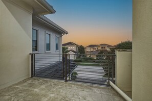 Ein Wohnbalkon mit einem Metallgitter, Fliesenboden und Häusern im Hintergrund.