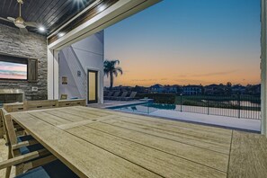Une terrasse extérieure moderne, dotée d’une piscine, de coins salon et offrant une vue sur le quartier au coucher du soleil.