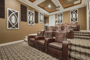 A home theater room with brown leather recliners, patterned carpet, and decorative wall panels. - Sun-Filled Haven with Sports Themed Game Room at Reunion (Reunion)