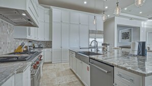Une cuisine moderne avec des meubles blancs, une cuisinière en acier inoxydable et un plan de travail en marbre.