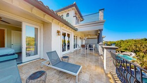 A spacious outdoor patio with a lounge chair, a dining area, and a pool. - Luxury Villa with Elegant Living Space at Reunion (Kissimmee)